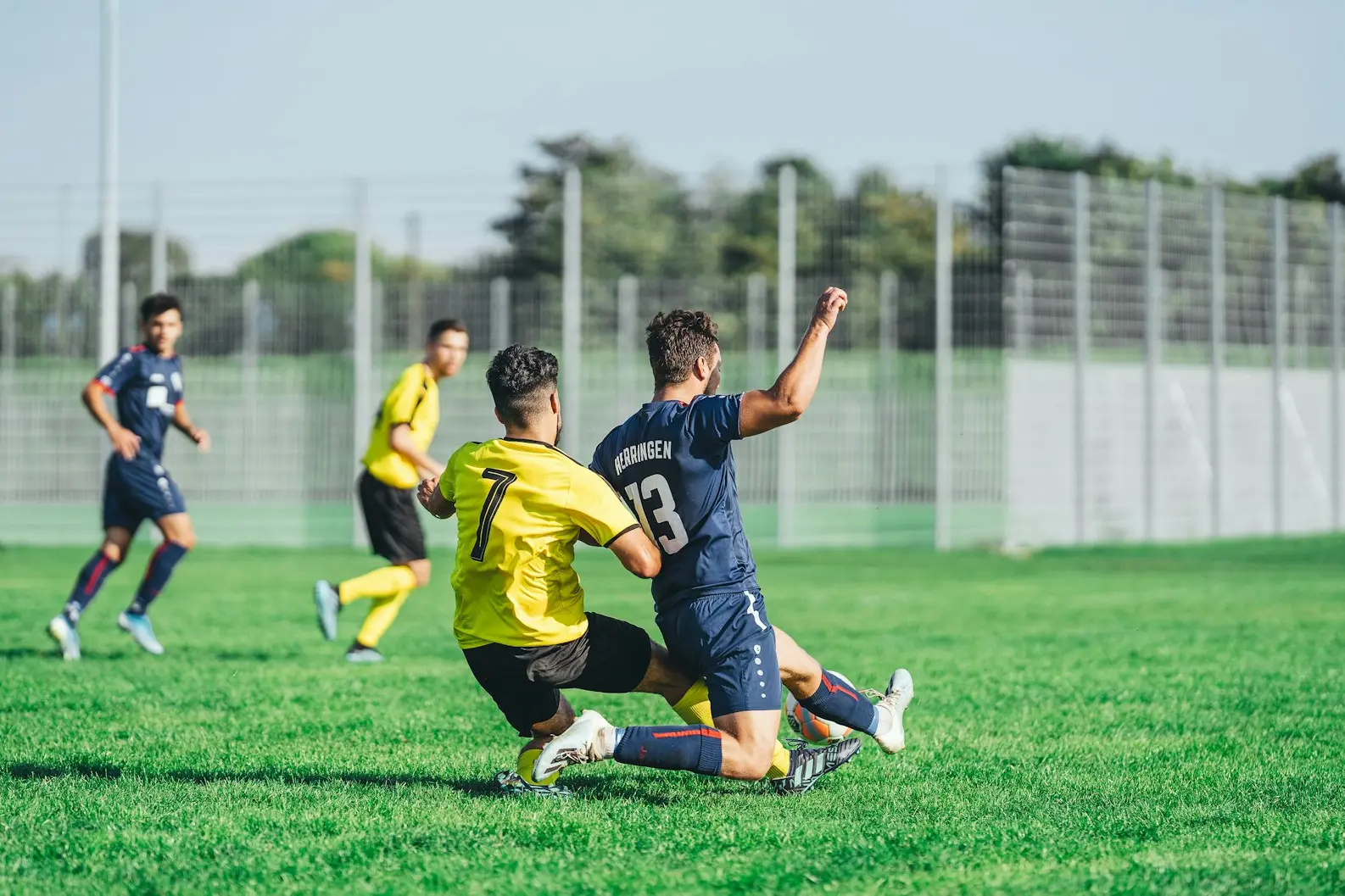 man in yellow and black jersey shirt kicking soccer ball on green grass field during daytime